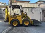 a yellow construction vehicle with a bucket on the side of the road