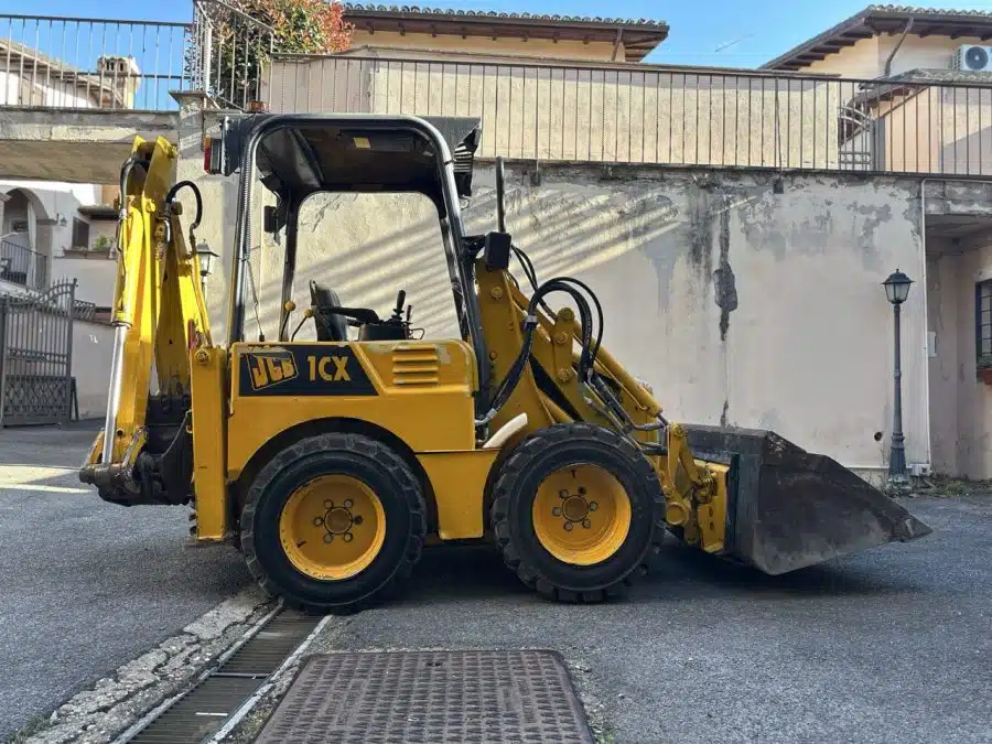 a yellow construction vehicle with a bucket on the side of the road