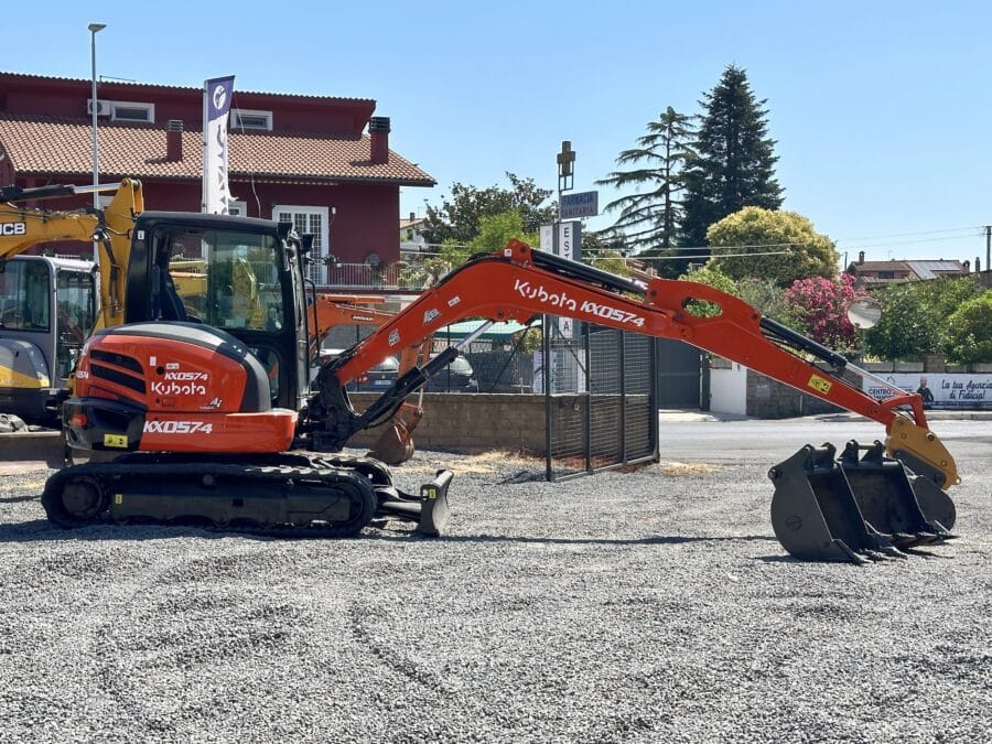 Mini-pelle Kubota KX57-4 vue latérale avec bras opérationnel et cabine fermée.