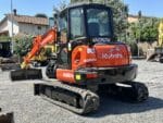 Kubota KX57-4 d'occasion avec bras monobloc, chenilles caoutchouc et structure compacte.