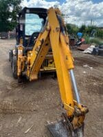 Braccio retroescavatore JCB con benna da scavo e cilindri idraulici in primo piano